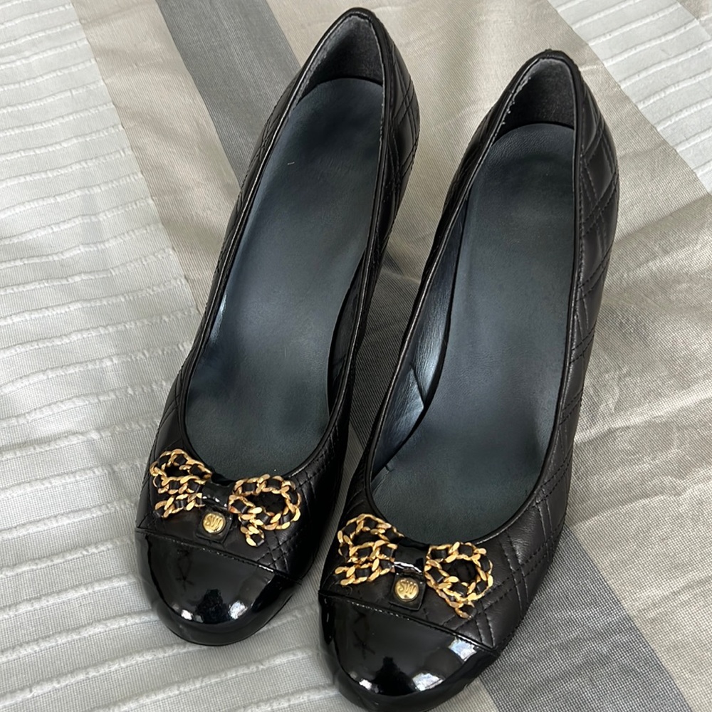 Stuart Weitzman quilted patent leather pumps with gold detail.